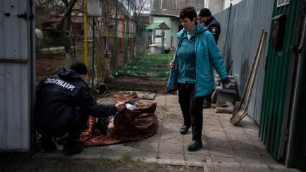 Un policía examina el cadáver de un hombre muerto durante la guerra con Rusia en Bucha, en las afueras de Kiev.