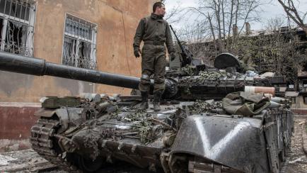 Un soldado ruso posa sobre uno de los tanques de Moscú 'decorados' con el símbolo nacional de la 'V'
