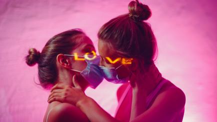 Portrait of two kissing couple young women in medical face mask.