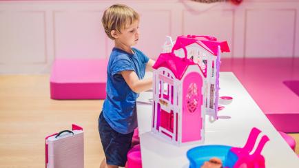 Imagen de archivo de un niño jugando con una casa de muñecas.