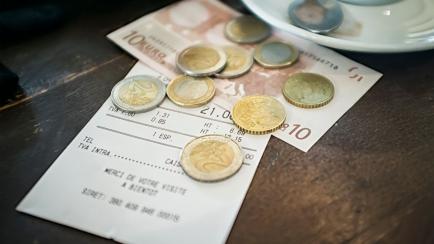 A bill with payment in Euros on the table of a cafe.