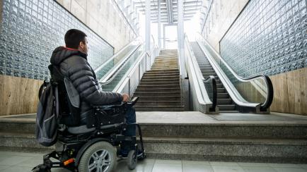 Rear View Of A Disabled Man On Wheelchair In Front Of Staircase