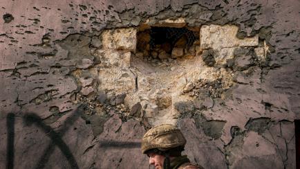 Un soldado ucraniano, ante un cráter en una casa atacada en Krymske, Lugansk. 