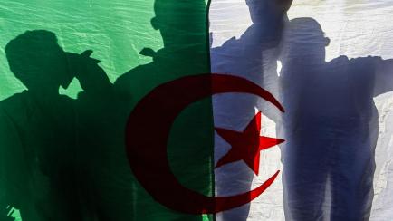 Varios ciudadanos se muestran tras una bandera de Argelia