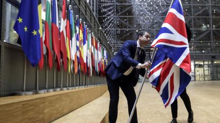 A member of protocol removes the Union flag from the atrium of the Europa building in Brussels, Friday, Jan. 31, 2020. As the United Kingdom prepared to bring to an end its 47-year EU membership, the bloc's top officials on Friday pledged to con...