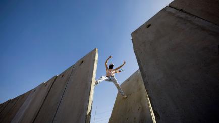 Un manifestante palestino hace gestos de victoria encaramado al muro de separación con Israel en Nilin, Cisjordania, en 2009. 