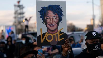 People in the crowd hold up an image of Stacey Abrams as President-elect Joe Biden speaks in Atlanta, Monday, Jan. 4, 2021, to campaign for Georgia Democratic candidates for U.S. Senate, Rev. Raphael Warnock and Jon Ossoff. (AP Photo/Carolyn Kaster)