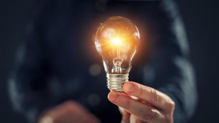 Creative new idea. Innovation, brainstorming, inspiration and solution concepts. The man is holding light bulb. Copy space background.