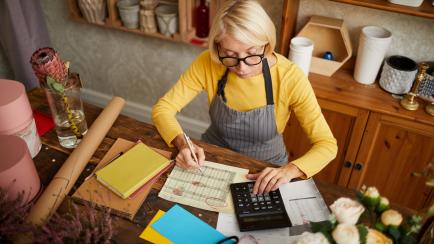 High angle portrait of female businesswoman counting finances using calculator in small shop, copy space