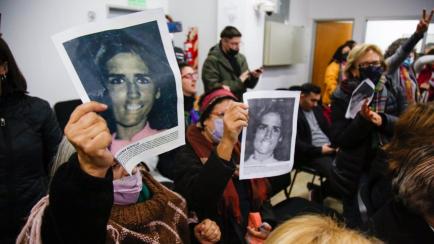 Varias personas sostienen imágenes de personas desaparecidas durante la dictadura militar en Argentina.