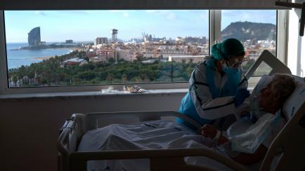 Ana Aguilar, 20, a nursing assistant, feeds one of her patients at the COVID-19 ward at the hospital del Mar in Barcelona, Spain, Wednesday, Nov. 18, 2020. Aguilar asked one of her patients, who was in the last days of her life, if there was any...