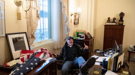 A supporter of US President Donald Trump sits inside the office of US Speaker of the House Nancy Pelosi as he protest inside the US Capitol in Washington, DC, January 6, 2021. - Demonstrators breeched security and entered the Capitol as Congress...