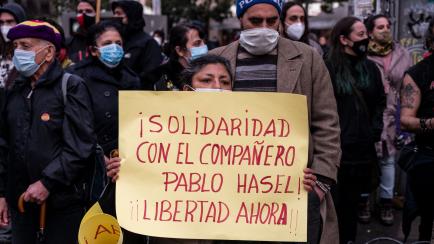 MADRID, SPAIN - 2021/02/06: A protester holds a placard with the words 'solidarity with comrade Pablo Hasel. Freedom now. ' from here during a demonstration to protest against the Spanish National Court's decision to sentence Catalan rapper Pabl...