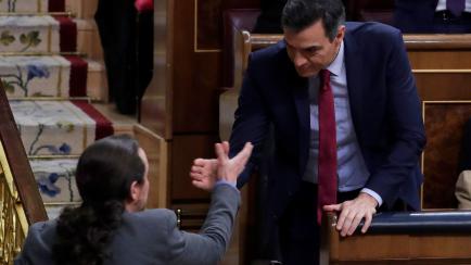 Spain's caretaker Prime Minister Pedro Sanchez and Podemos party leader Pablo Iglesias, left, clasp hands at the Spanish Parliament in Madrid, Spain, Tuesday, Jan. 7, 2020. Spain's Parliament chose Socialist leader Pedro Sánchez to form a new g...
