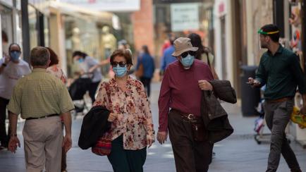 SEVILLE, SPAIN - MAY 19: Several people protected by masks are walking in a downtown street, following the new Government agreement in which the use of masks will be mandatory also in public streets and in closed spaces when compliance with the ...