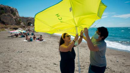 People place a beach umbrella at La Arana Beach in Malaga on June 7, 2020, as lockdown measures are eased during the novel coronavirus COVID-19 pandemic. (Photo by JORGE GUERRERO / AFP) (Photo by JORGE GUERRERO/AFP via Getty Images)