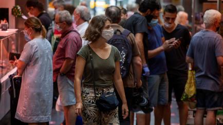 Customers buy fish and meat at a market in Barcelona, Spain, Friday, July 17, 2020. Health authorities are asking Barcelona's 5.5 million residents to reduce their socialization to a minimum and to stay at home as much as possible to stem the sp...