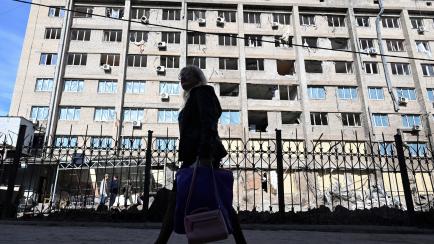 Una mujer camina junto a un edificio destruido en Donetsk.