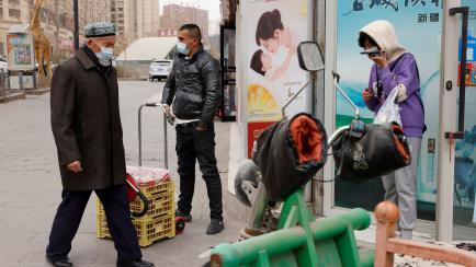 Residentes con mascarillas pasean en la ciudad de Aksu, en Xinjiang, región china donde vive la mayoría de los uigur.