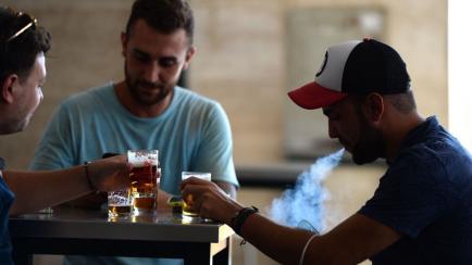 Un hombre fuma mientras bebe una cerveza en una terraza de un bar en Sevilla.