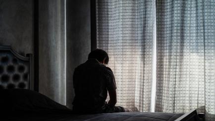 Un hombre, deprimido, sobre su cama.