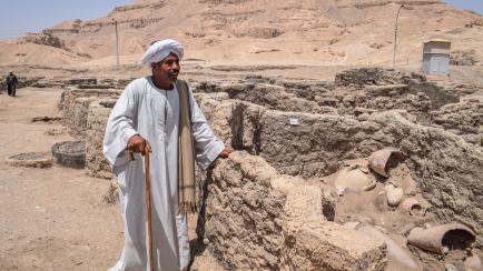 Aly Farouk, trabajador jefe de la excavación, de pie junto a los restos de la "ciudad perdida" de Luxor, una urbe de 3.000 años de antigüedad que esconde una fascinante historia.
