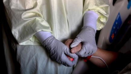 Una enfermera agarra la mano de un paciente con coronavirus