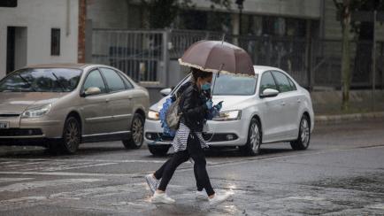 Unas chicas cruzan una calle de Sevilla bajo la lluvia. 