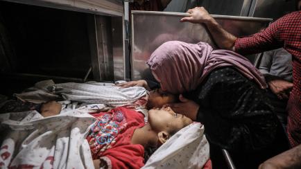 Una madre besa a sus hijos, muertos en un ataque de Israel, en la morgue del hospital de Beit Hanoun, Gaza, el pasado 10 de mayo. 