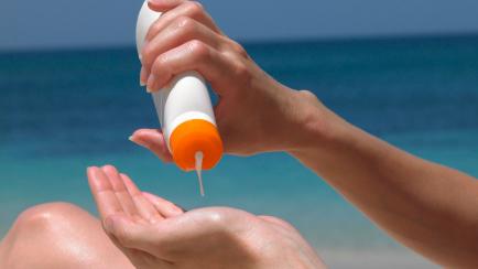 Una mujer se aplica crema solar en la playa.