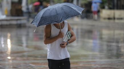 Una persona refugiada bajo un paraguas de la lluvia el pasado mes de julio en Valencia.