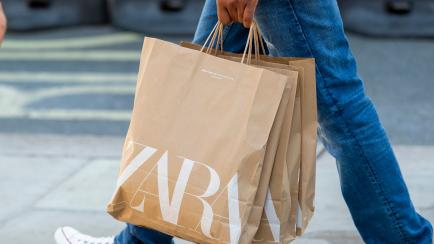 Un hombre lleva varias bolsas con ropa de Zara.