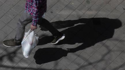 Un hombre porta bolsas de la compra, en las calles de Madrid. 