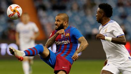 El defensa del FC Barcelona Dani Alves despeja un balón junto al delantero del Real Madrid Vinicius Jr.