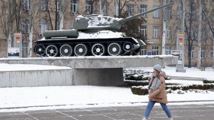 Una mujer camina delante de una estatua de la II Guerra Mundial en Ucrania.