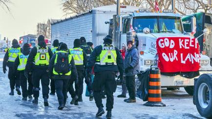 Agentes policiales pasan junto a la zona donde se concentran las protestas de los grupos antivacunas, en Ottawa, este domingo.