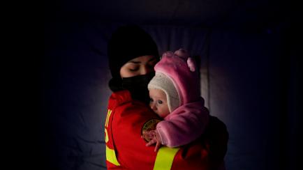 Una trabajadora de los servicios de emergencia abraza a un bebé llegado desde Ucrania en Siret, Rumanía, este sábado. 