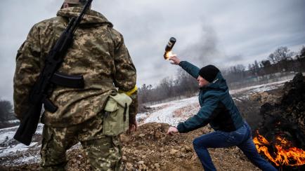 Un civil ucraniano, junto a un soldado, lanza un cóctel molotov para detener el avance de las tropas rusas en Zhithómir.