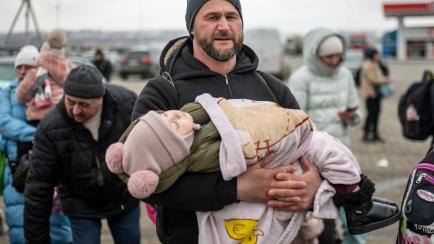 Un hombre, con su bebé, en la frontera de Ucrania.
