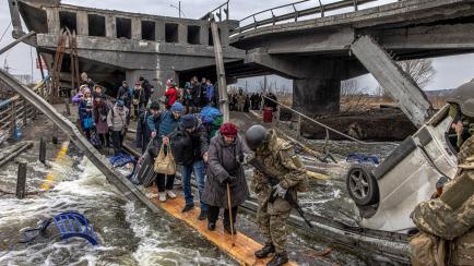 Civiles ucranianos cruzan uno de los puentes volados por las tropas de dicho país, en Irpín.
