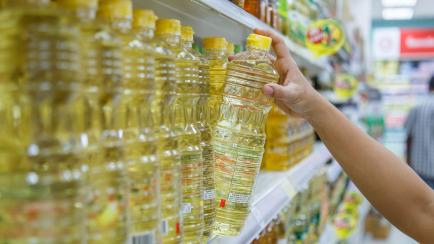 Una persona comprando aceite de girasol en un supermercado.