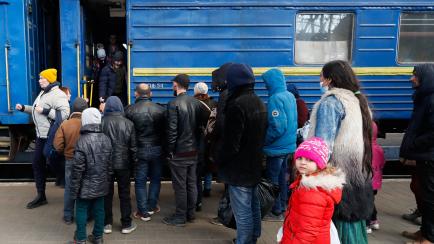 Un grupo de refugiados intenta subirse a un tren para salir del país.