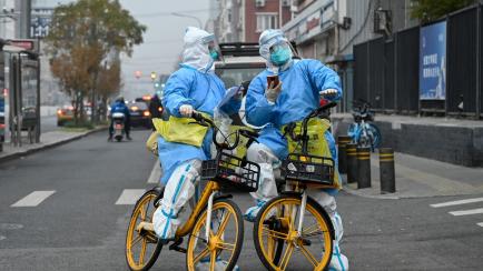 Sanitarios chinos con EPI transportan pruebas de covid por las calles de Pekín, este 24 de noviembre. 