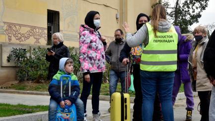 Varios refugiados ucranianos hablan con una traductoria frente al Palacio Victoria Eugenia de Barcelona, reconvertido en centro de recepción, el 18 de marzo. 