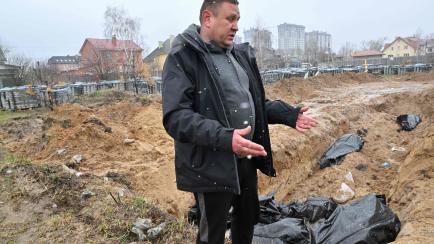Un hombre muestra los cadáveres localizados en una fosa común en la ciudad de Bucha, a las afueras de Kiev.