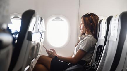 Una mujer en un avión con el móvil. 