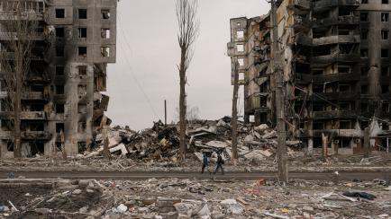 Unas personas caminan junto a un edificio de apartamentos destruido durante los combates entre las fuerzas ucranianas y rusas en Borodianka.