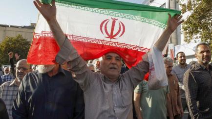 Foto de archivo de un hombre sosteniendo una bandera de Irán en una de las protestas por la muerte de Mahsa Amini.