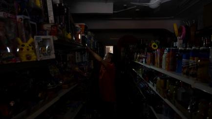 El dueño de una tienda en el centro de Santa Cruz coloca luces provisionales mientras espera a que se restablezca el suministro eléctrico la isla.
