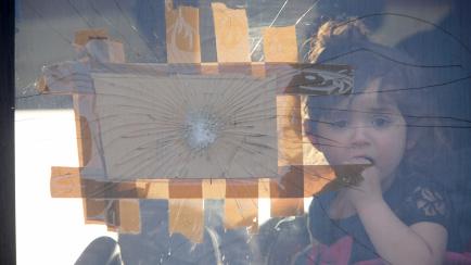 A Syrian refugee child looks through a shattered glass window of a bus as she arrives at the Syrian-Lebanese border of Jdaydet Yabous, Syria, April 18, 2018. REUTERS/Omar Sanadiki